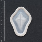 Cross Carving - Silicone makeup prosthetic in vanilla shade on a black surface with a ruler