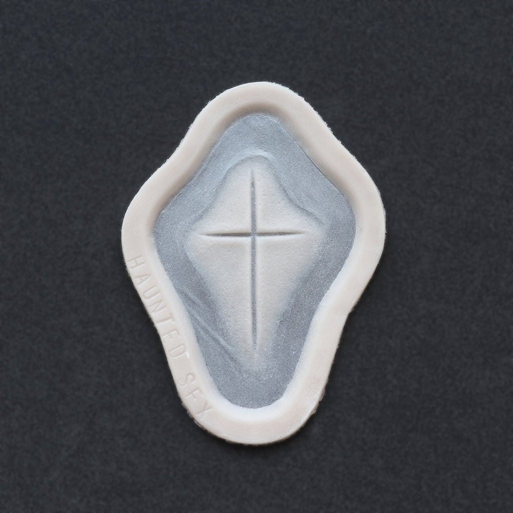 Cross Carving - Silicone makeup prosthetic in vanilla shade on a black surface