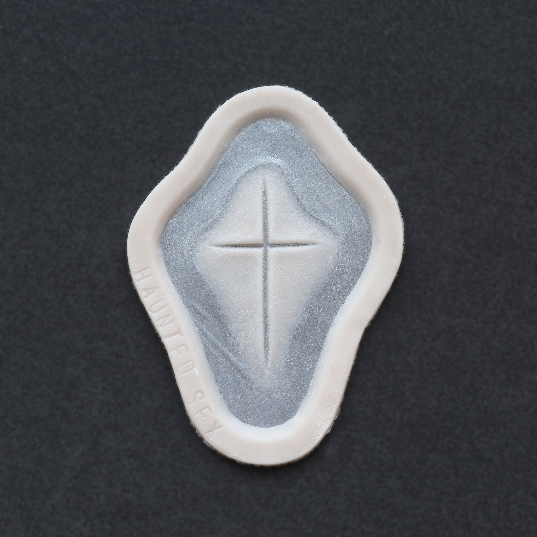 Cross Carving - Silicone makeup prosthetic in vanilla shade on a black surface