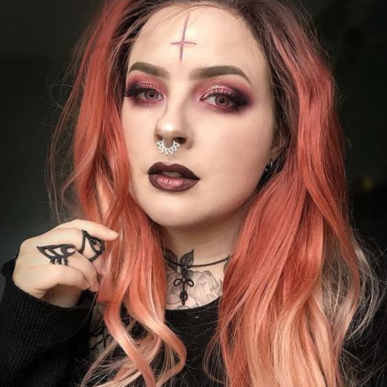 Woman with long ginger hair wearing a cross carving in vanilla shade and red makeup