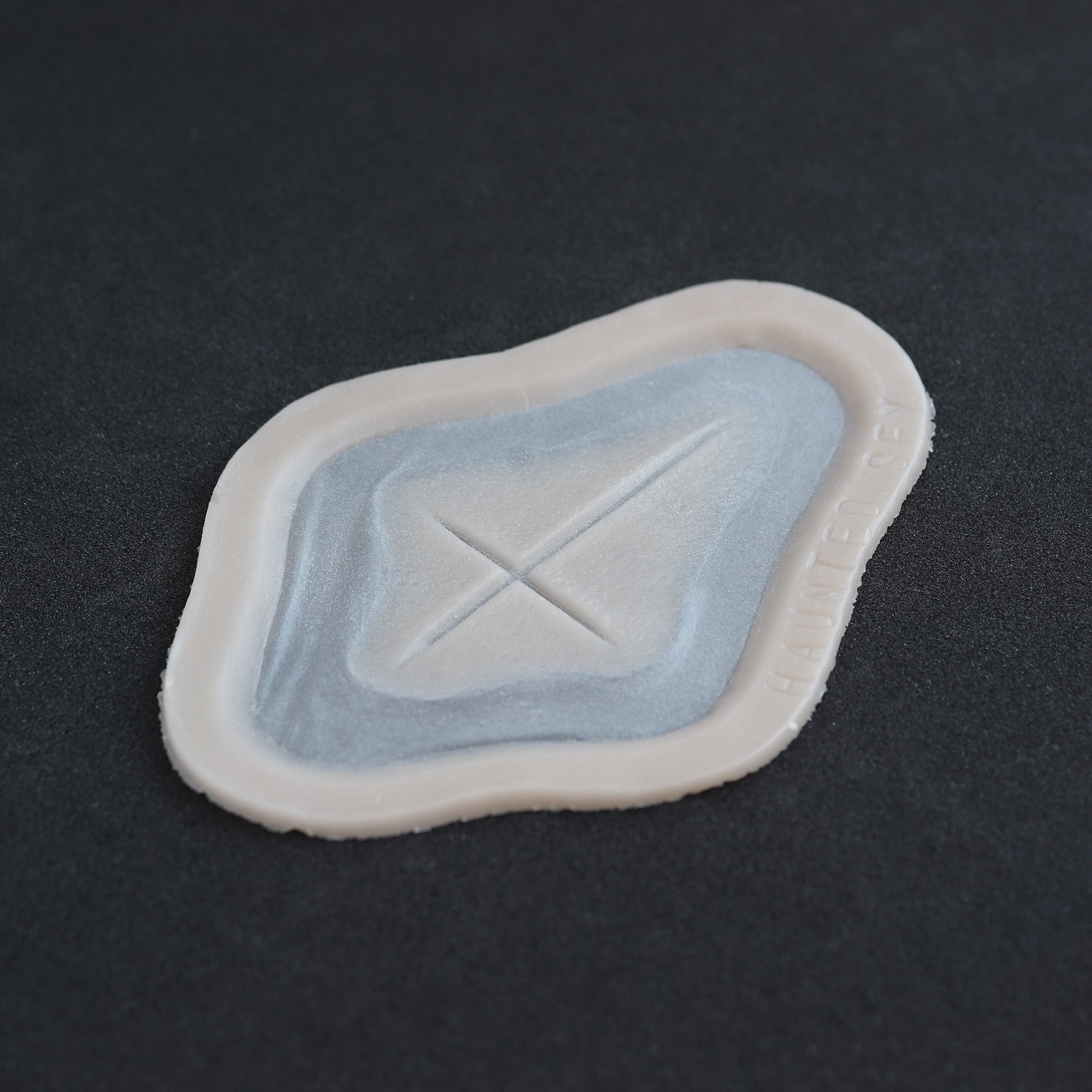 Cross Carving - Silicone makeup prosthetic in vanilla shade on a black surface