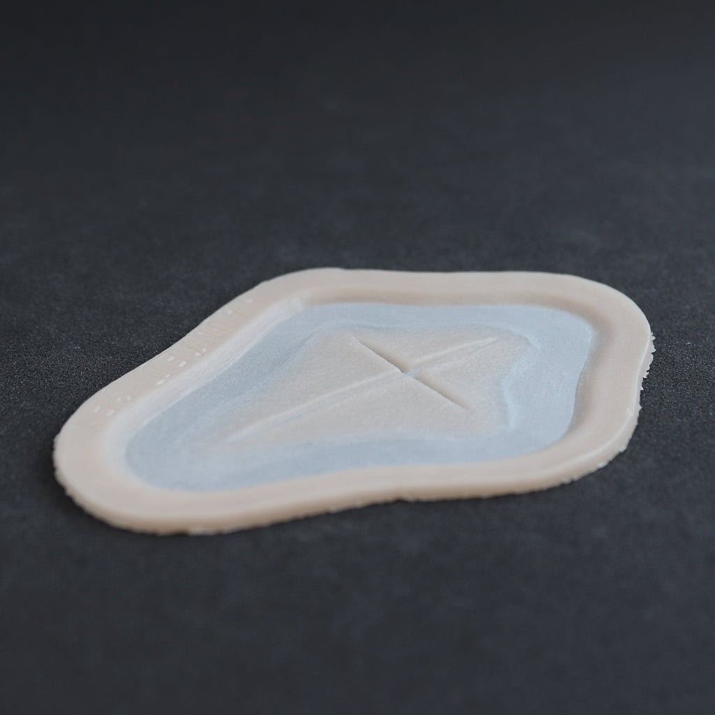 Cross Carving - Silicone makeup prosthetic in vanilla shade on a black surface