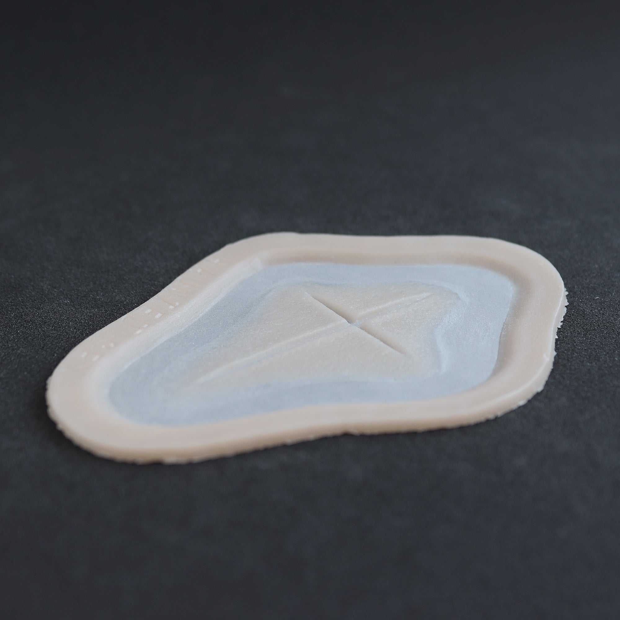 Cross Carving - Silicone makeup prosthetic in vanilla shade on a black surface