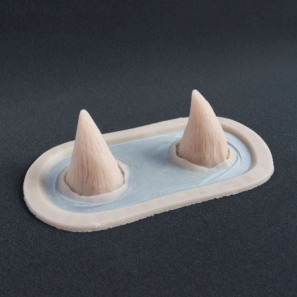 Devil Horns - Silicone makeup prosthetic in vanilla shade on a black surface