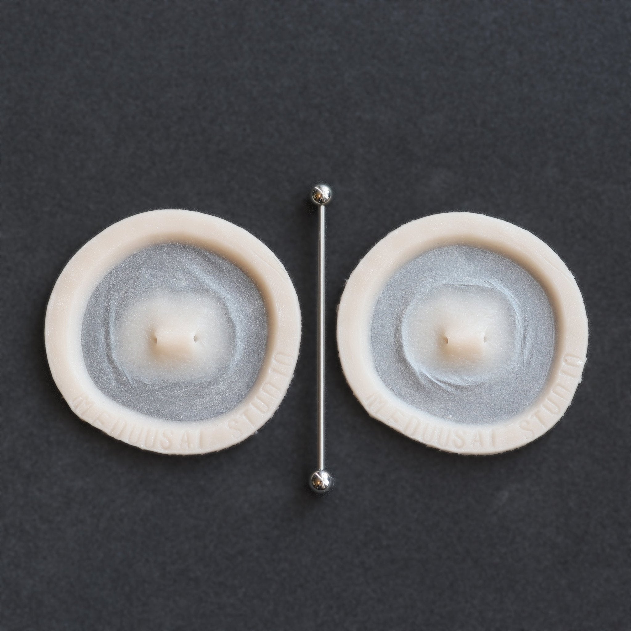 Double Surface Piercing - Silicone makeup prosthetic in vanilla shade on a black surface