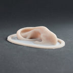 Extra Ears - Silicone makeup prosthetic in vanilla shade on a black surface