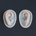Extra Ears - Silicone makeup prosthetic in vanilla shade on a black surface