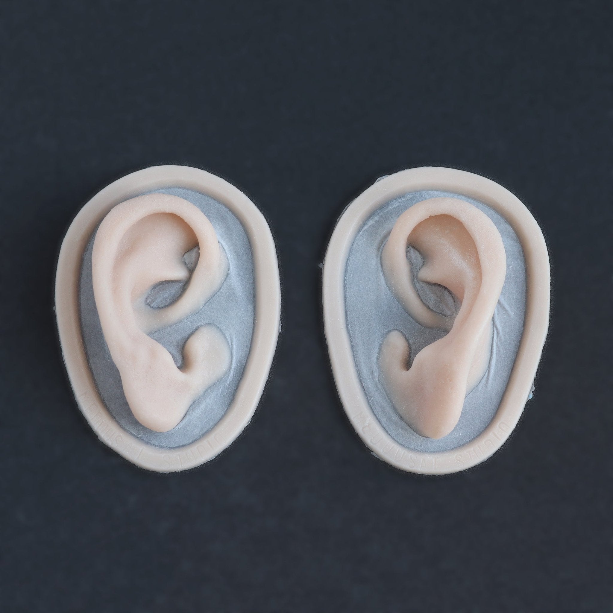 Extra Ears - Silicone makeup prosthetic in vanilla shade on a black surface