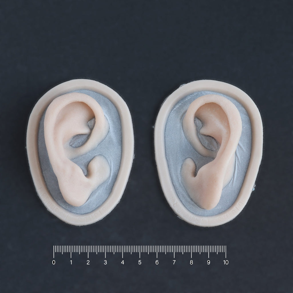 Extra Ears - Silicone makeup prosthetic in vanilla shade on a black surface with a ruler