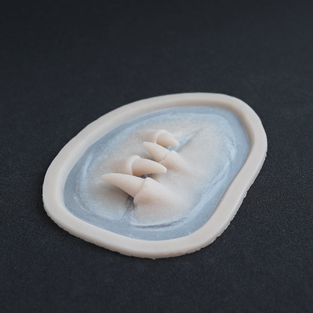 Facial Fangs 2.0 - Silicone makeup prosthetic in vanilla shade on a black surface