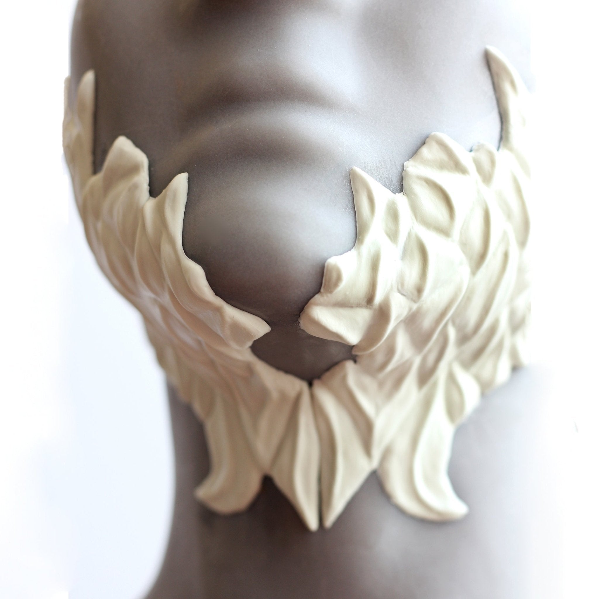 Mannequin wearing white facial scale prosthetics