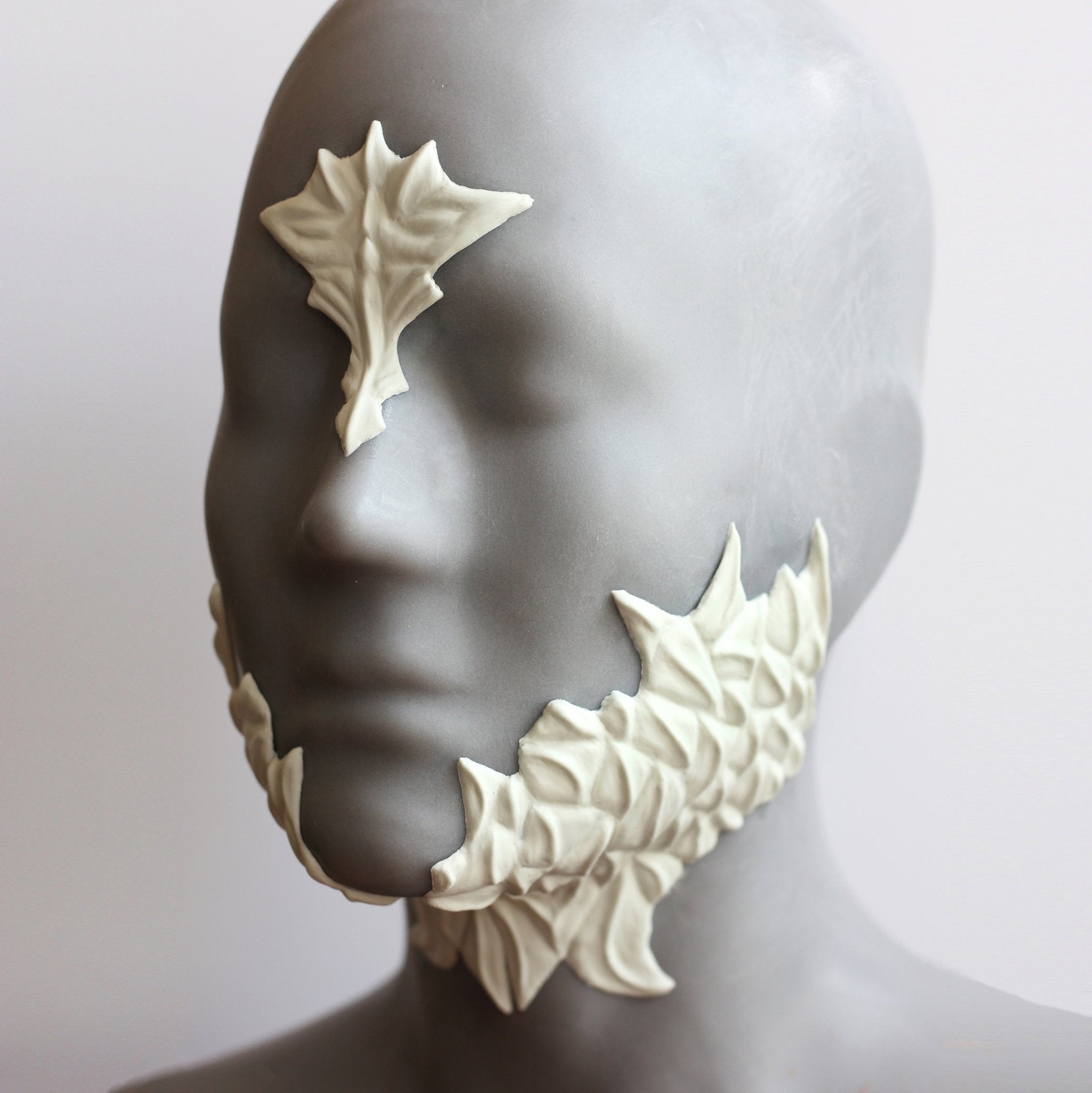 Mannequin wearing white facial scale prosthetics