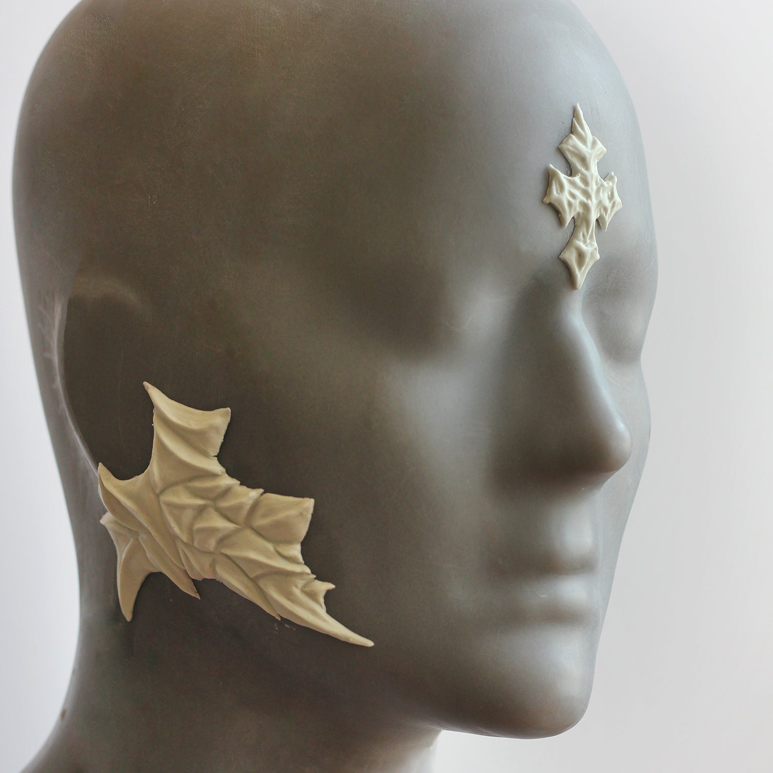 Mannequin wearing white facial scale prosthetics