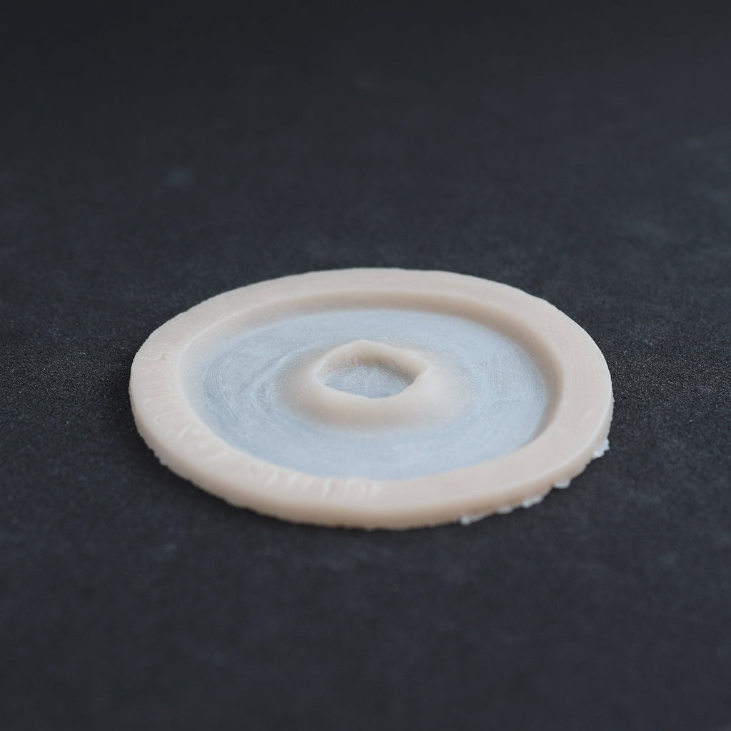 Gunshot Entry Wound - Silicone makeup prosthetic in vanilla shade on a black surface