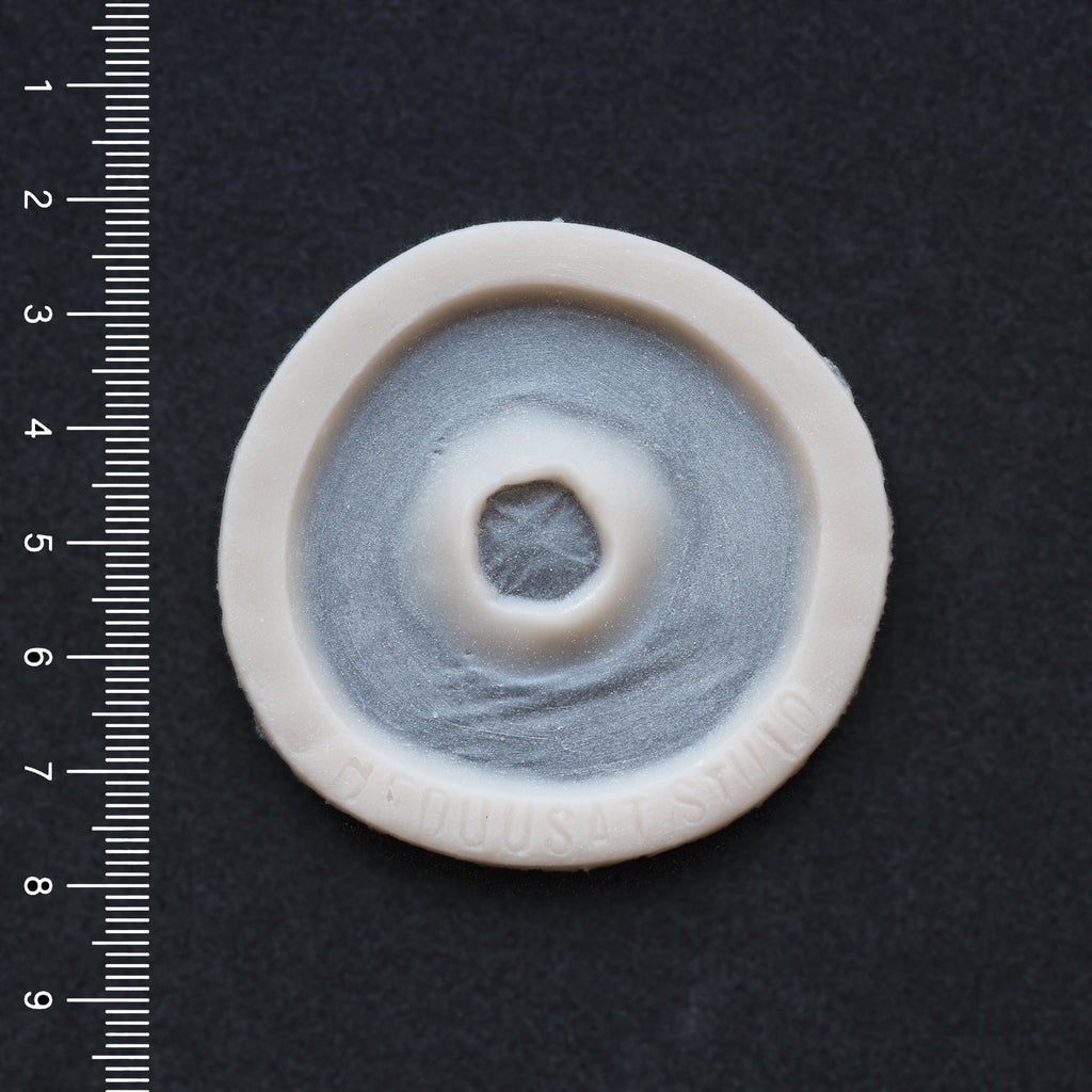 Gunshot Entry Wound - Silicone makeup prosthetic in vanilla shade on a black surface with a ruler