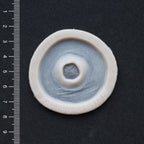 Gunshot Entry Wound - Silicone makeup prosthetic in vanilla shade on a black surface with a ruler