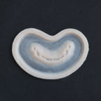 Half Bite - Silicone makeup prosthetic in vanilla shade on a black surface