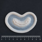 Half Bite - Silicone makeup prosthetic in vanilla shade on a black surface with a ruler