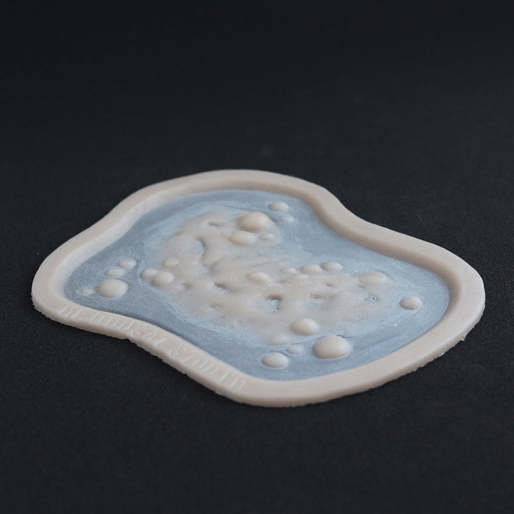 Infected Bite - Silicone makeup prosthetic in vanilla shade on a black surface