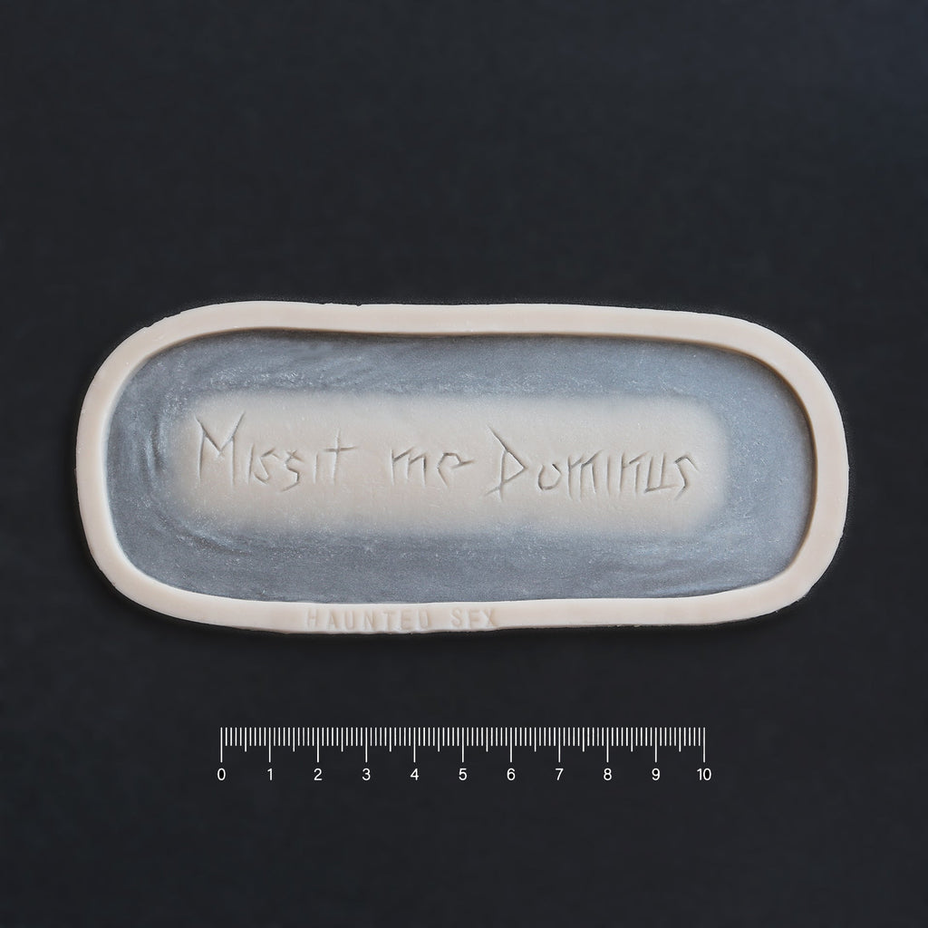 Missit Me Dominus Carving (The Lord Has Sent Me) - Silicone prosthetic in vanilla shade on a black surface with a ruler