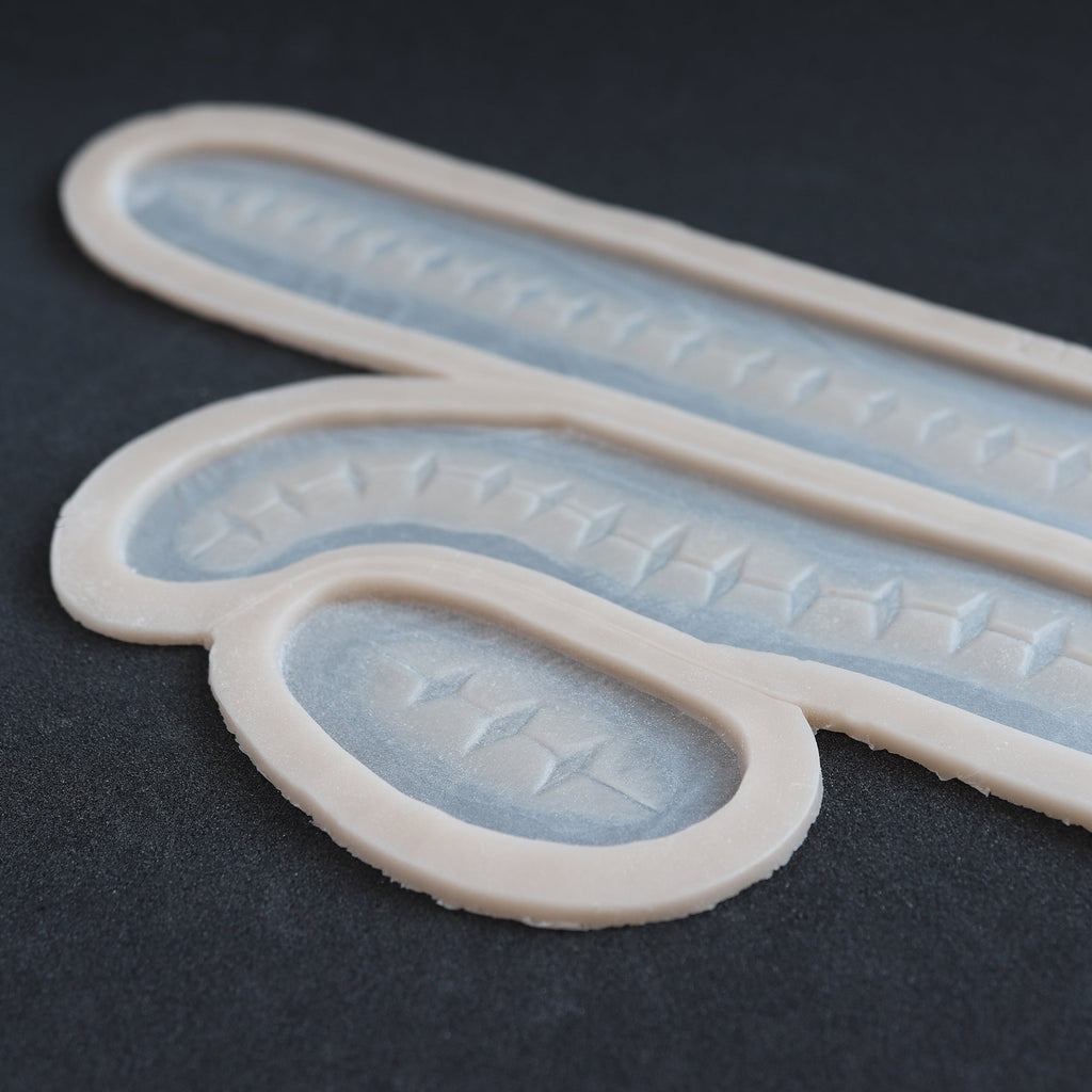 Scarification Strips - Silicone makeup prosthetic in vanilla shade on a black surface