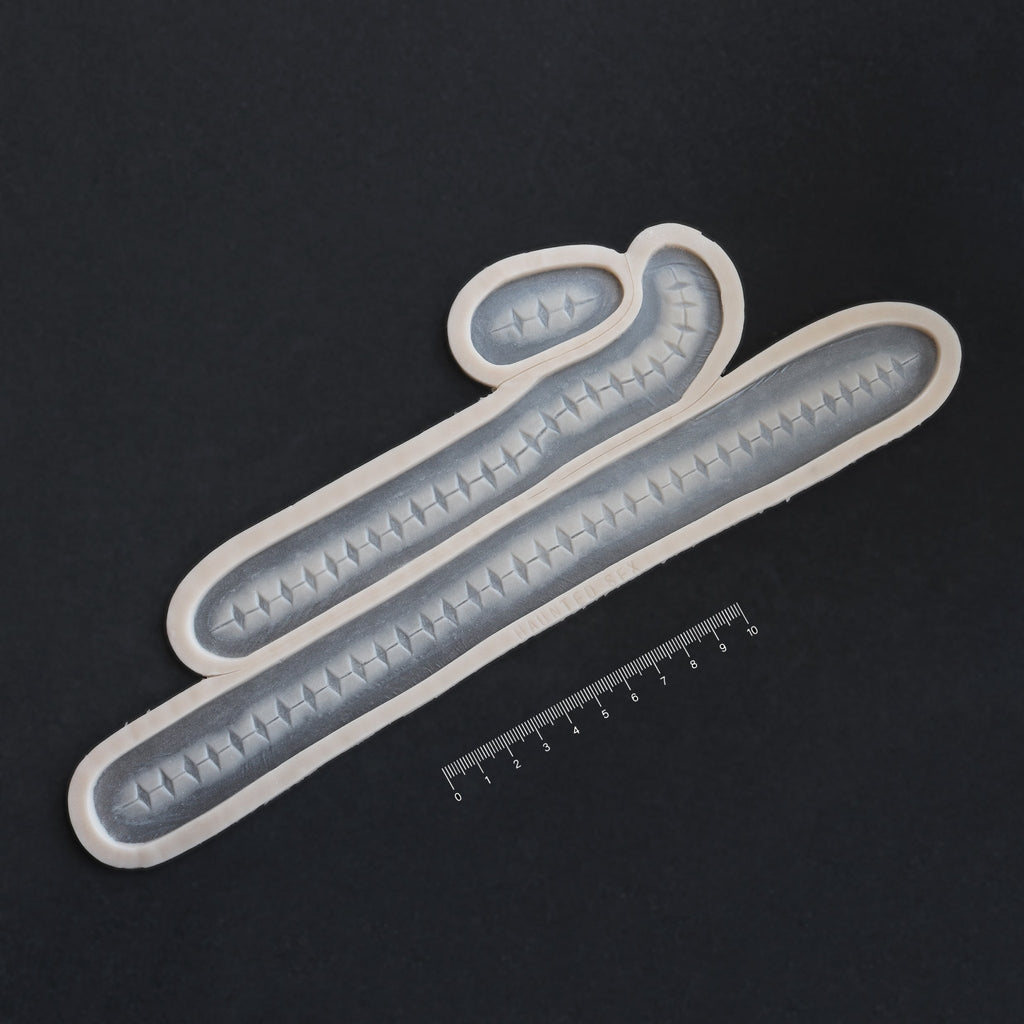 Scarification Strips - Silicone makeup prosthetic in vanilla shade on a black surface with a ruler