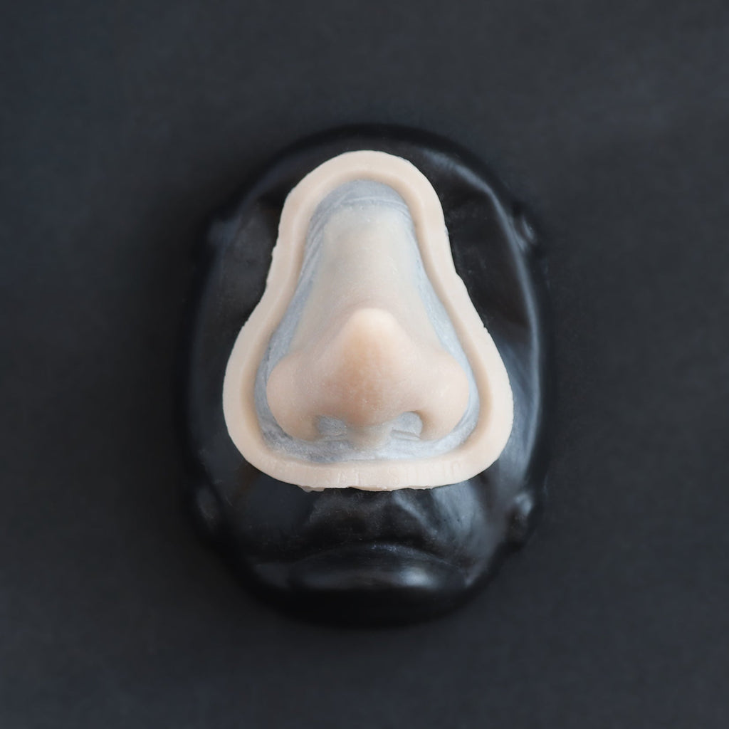Short Pointy Nose - Silicone makeup prosthetic in vanilla shade on a black surface