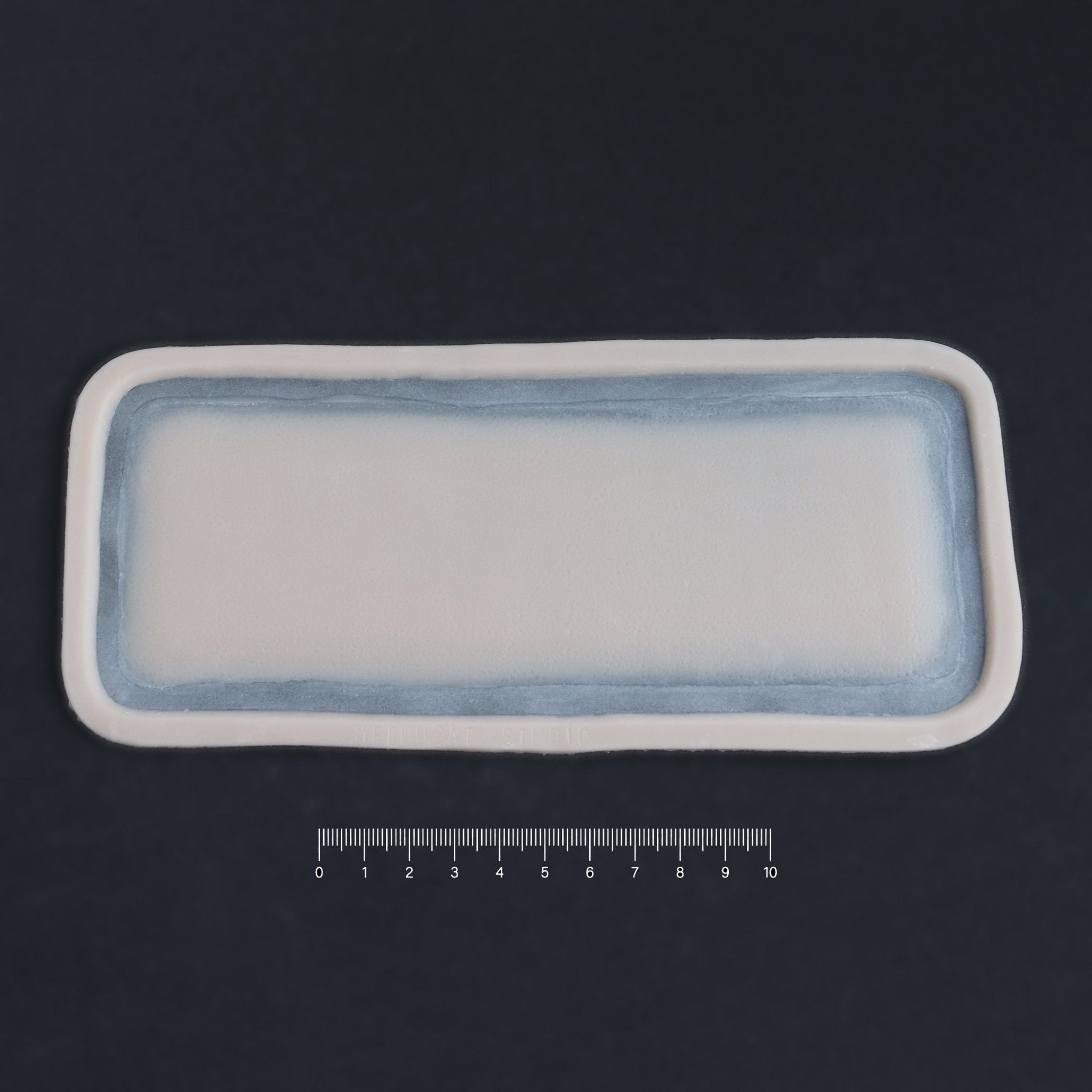 Long Silicone Patch - Silicone makeup prosthetic in vanilla shade on a black surface with a ruler