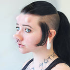 Woman with black hair wearing subdermal horns and a piglet nose prosthetic