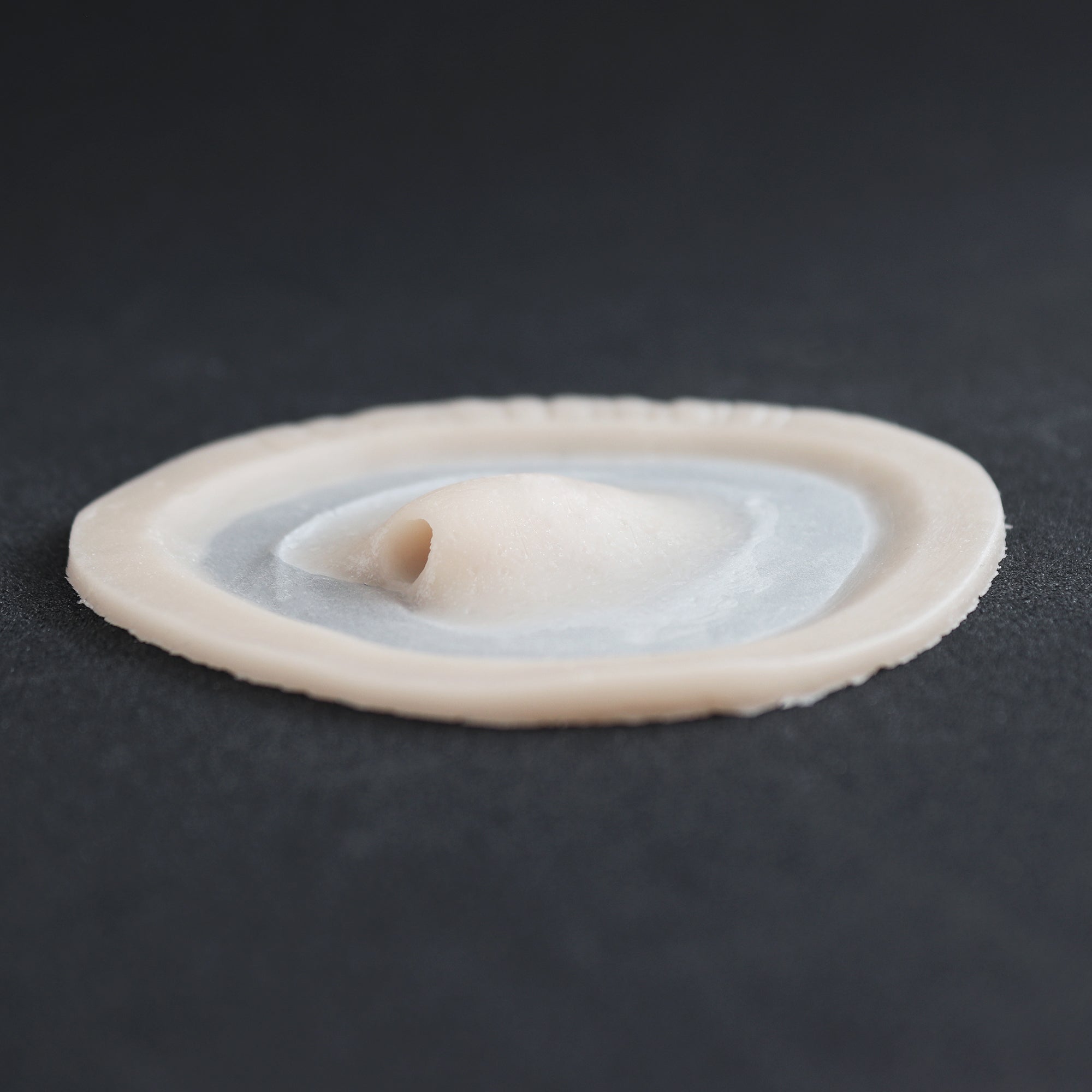 Skin Pocket 1 - Silicone makeup prosthetic in vanilla shade on a black surface