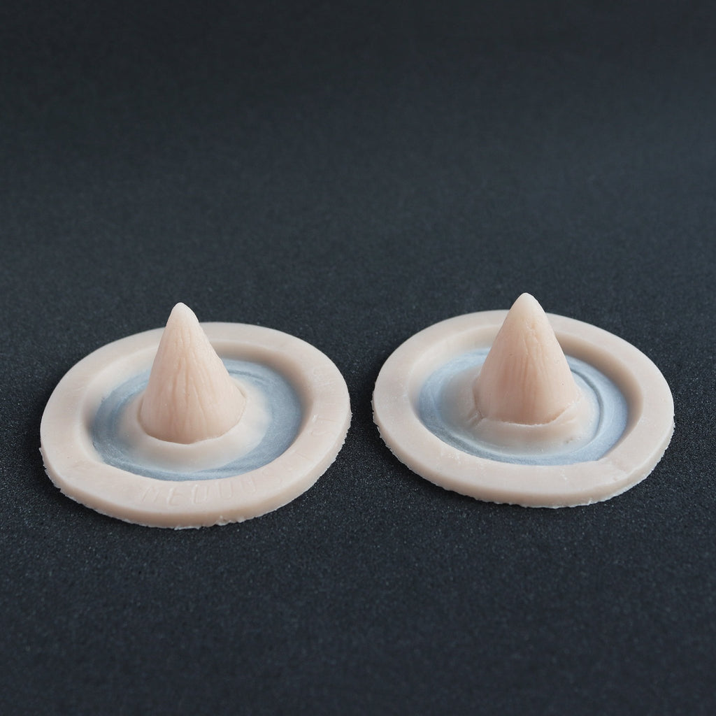 Small Devil Horns (Pair) - Silicone makeup prosthetic in vanilla shade on a black surface