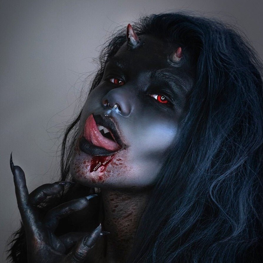 Woman in dark makeup wearing small devil horns