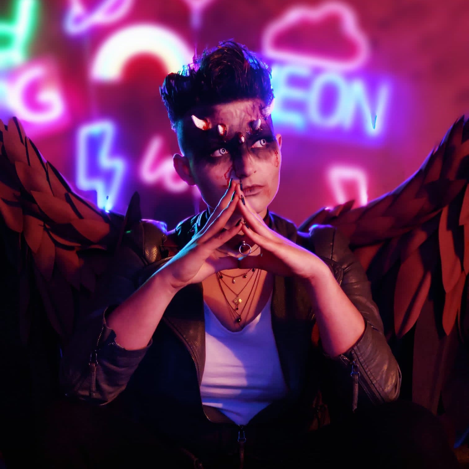 Woman with short hair wearing dark makeup, wings, and crooked horns prosthetics
