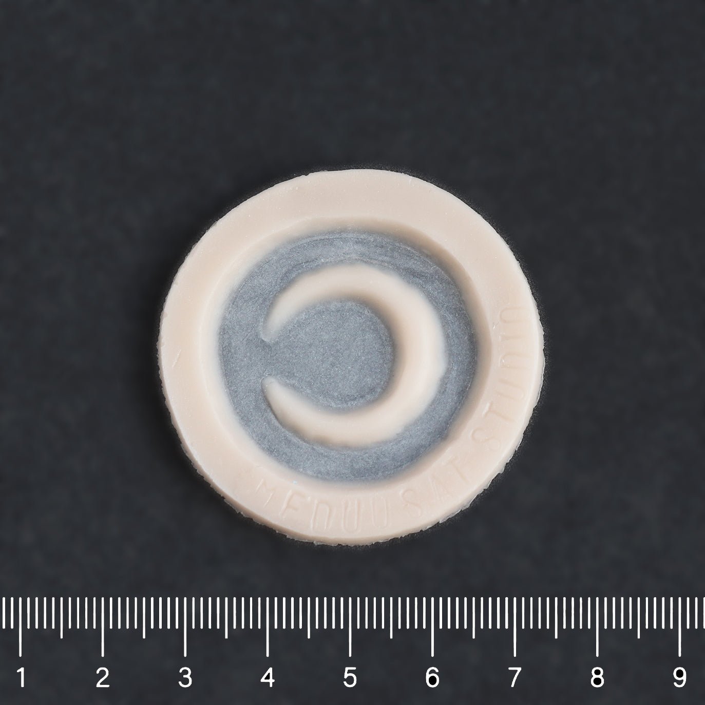 Small Moon - Silicone makeup prosthetic in vanilla shade on a black surface with a ruler