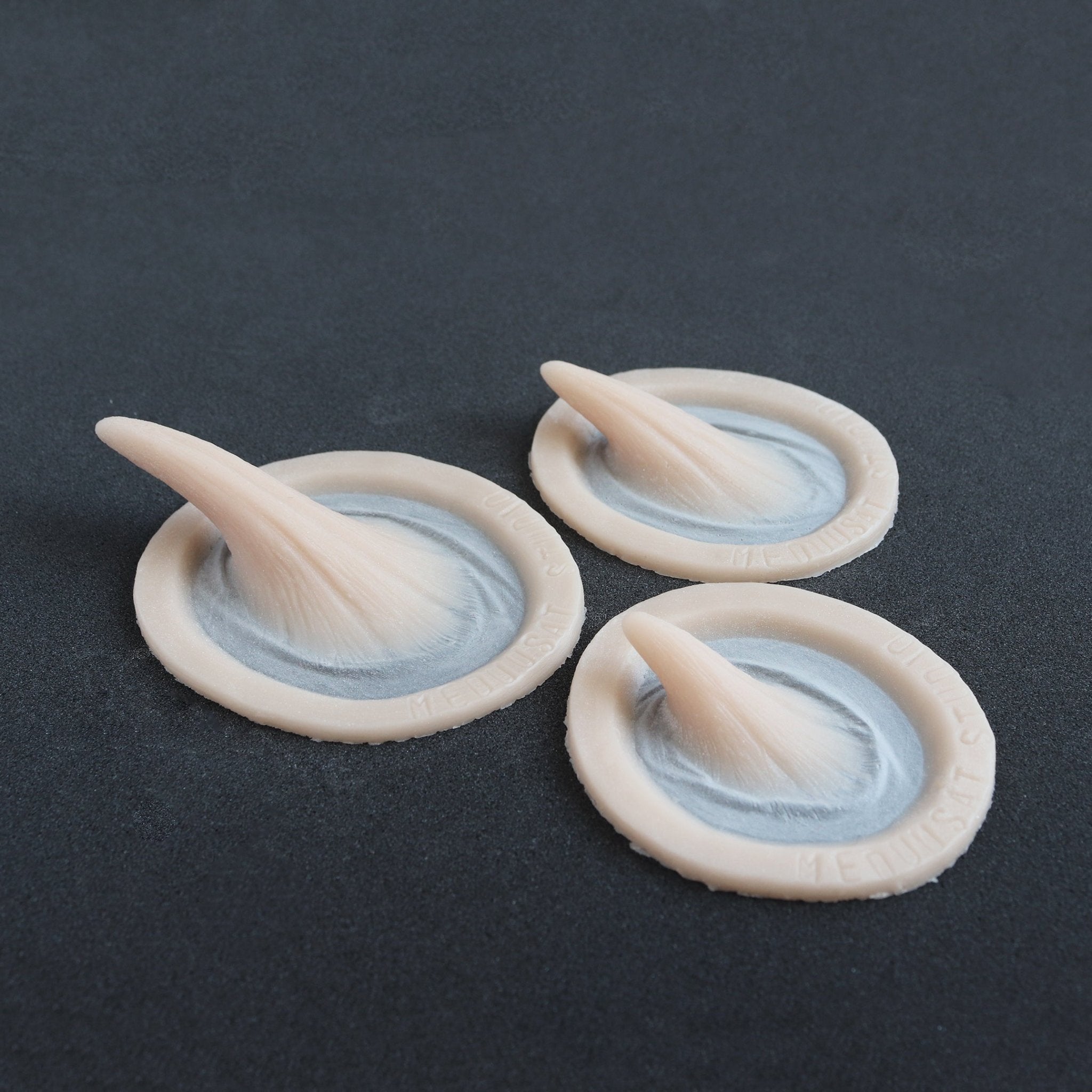 Small Vertical Horns (Pair) - Silicone makeup prosthetic in vanilla shade on a black surface