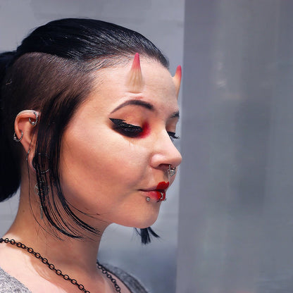 Woman with dark hair wearing red makeup and small vertical horns