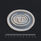 Stargate Goa'uld Mark - Silicone makeup prosthetic in vanilla shade on a black surface with a ruler