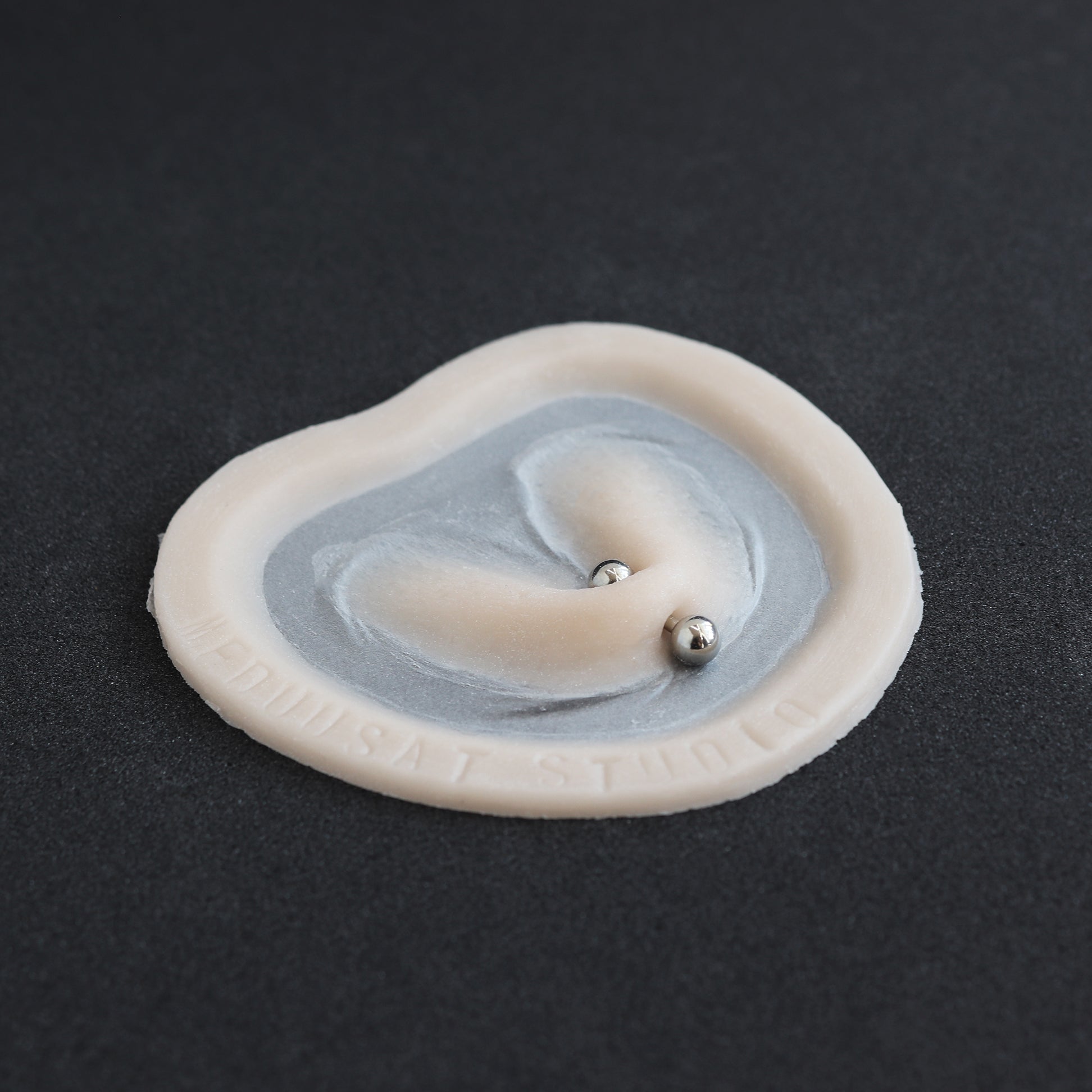 Stretched Piercing - Silicone makeup prosthetic in vanilla shade on a black surface