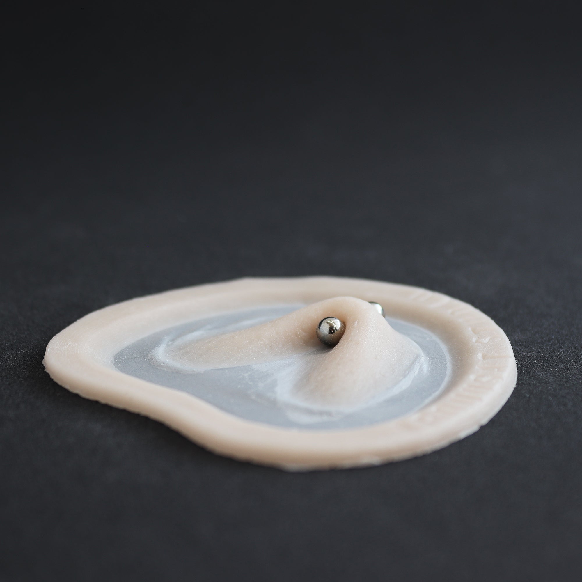Stretched Piercing - Silicone makeup prosthetic in vanilla shade on a black surface
