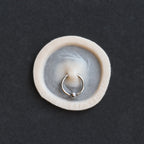 Surface Piercing - Silicone makeup prosthetic in vanilla shade on a black surface