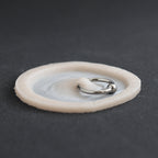 Surface Piercing - Silicone makeup prosthetic in vanilla shade on a black surface