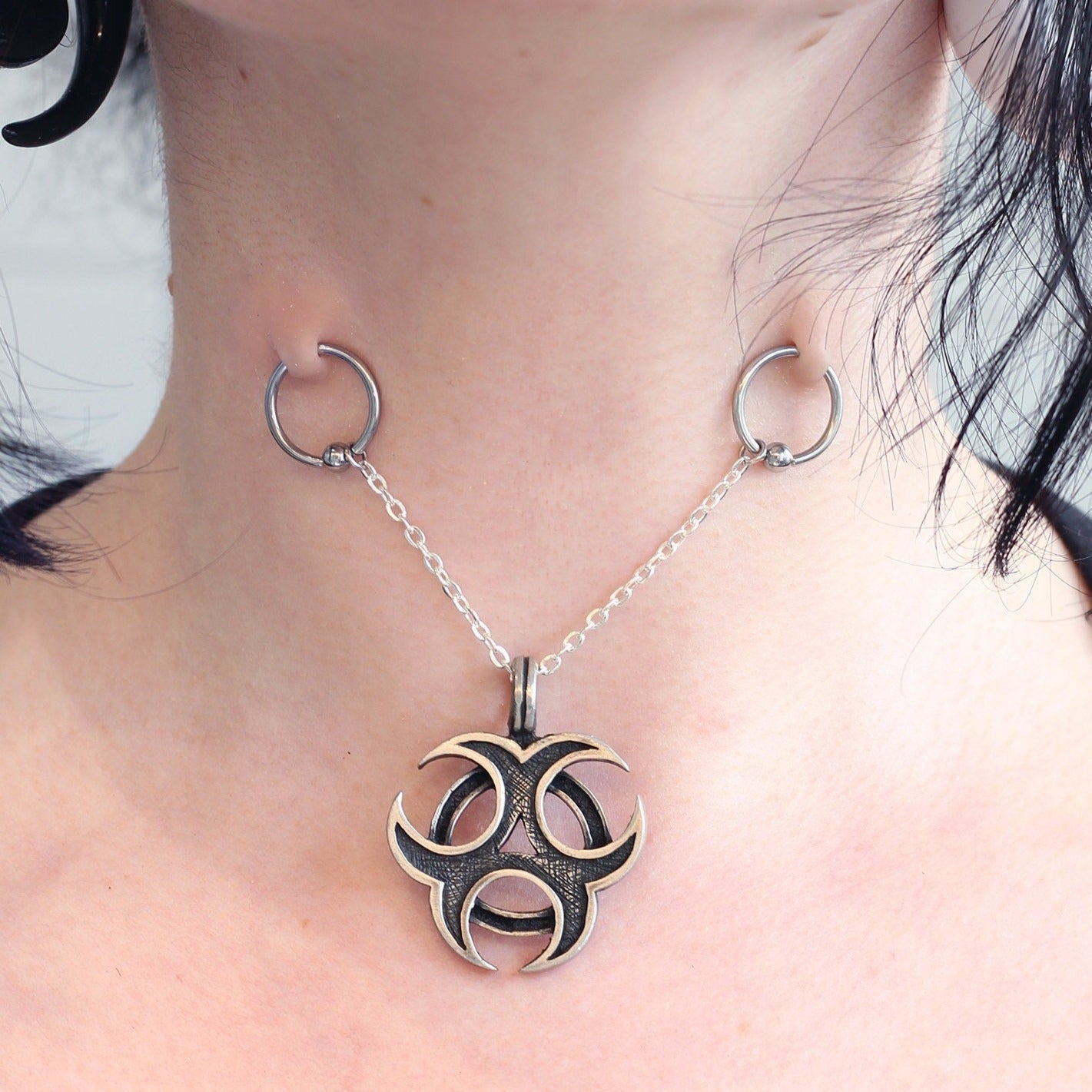 Woman's neck with two surface piercings and a necklace between them