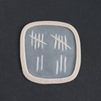 Tally Marks - Silicone makeup prosthetic in vanilla shade on a black surface