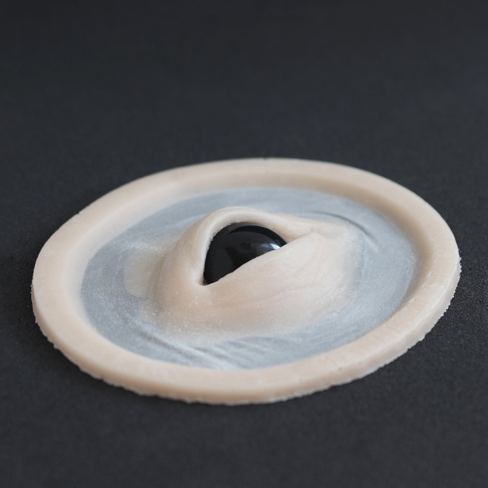 Third Eye - Silicone makeup prosthetic in vanilla shade on a black surface