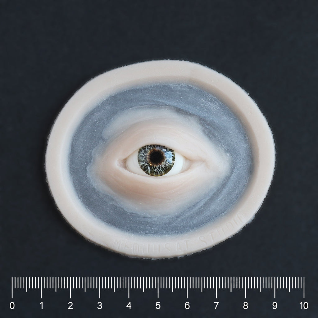 Third Eye - Silicone makeup prosthetic in vanilla shade on a black surface with a ruler