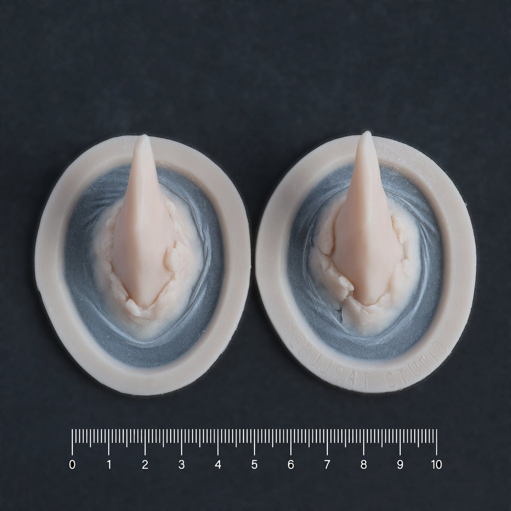 Torn Horns (Pair) - Silicone makeup prosthetic in vanilla shade on a black surface with a ruler