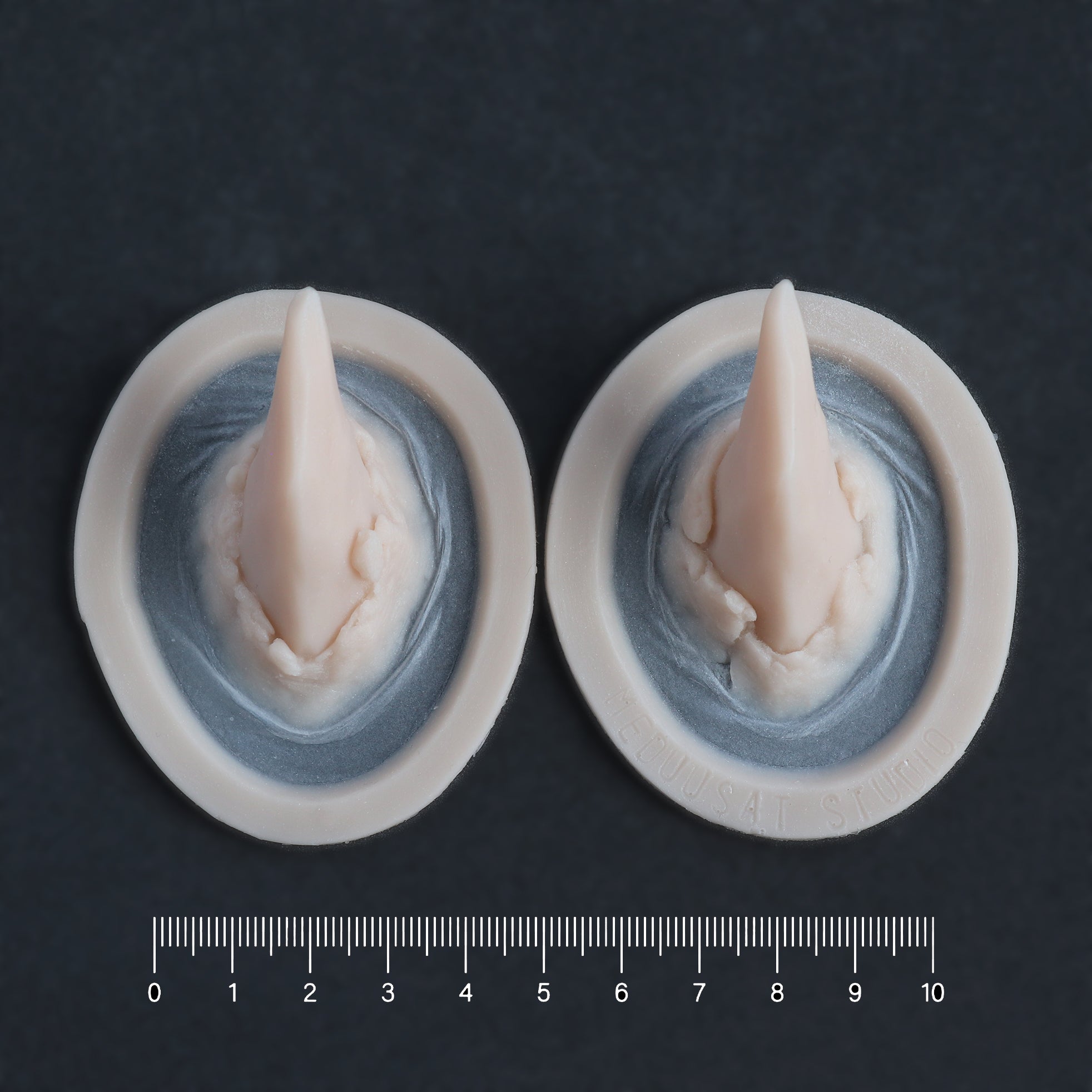 Torn Horns (Pair) - Silicone makeup prosthetic in vanilla shade on a black surface with a ruler