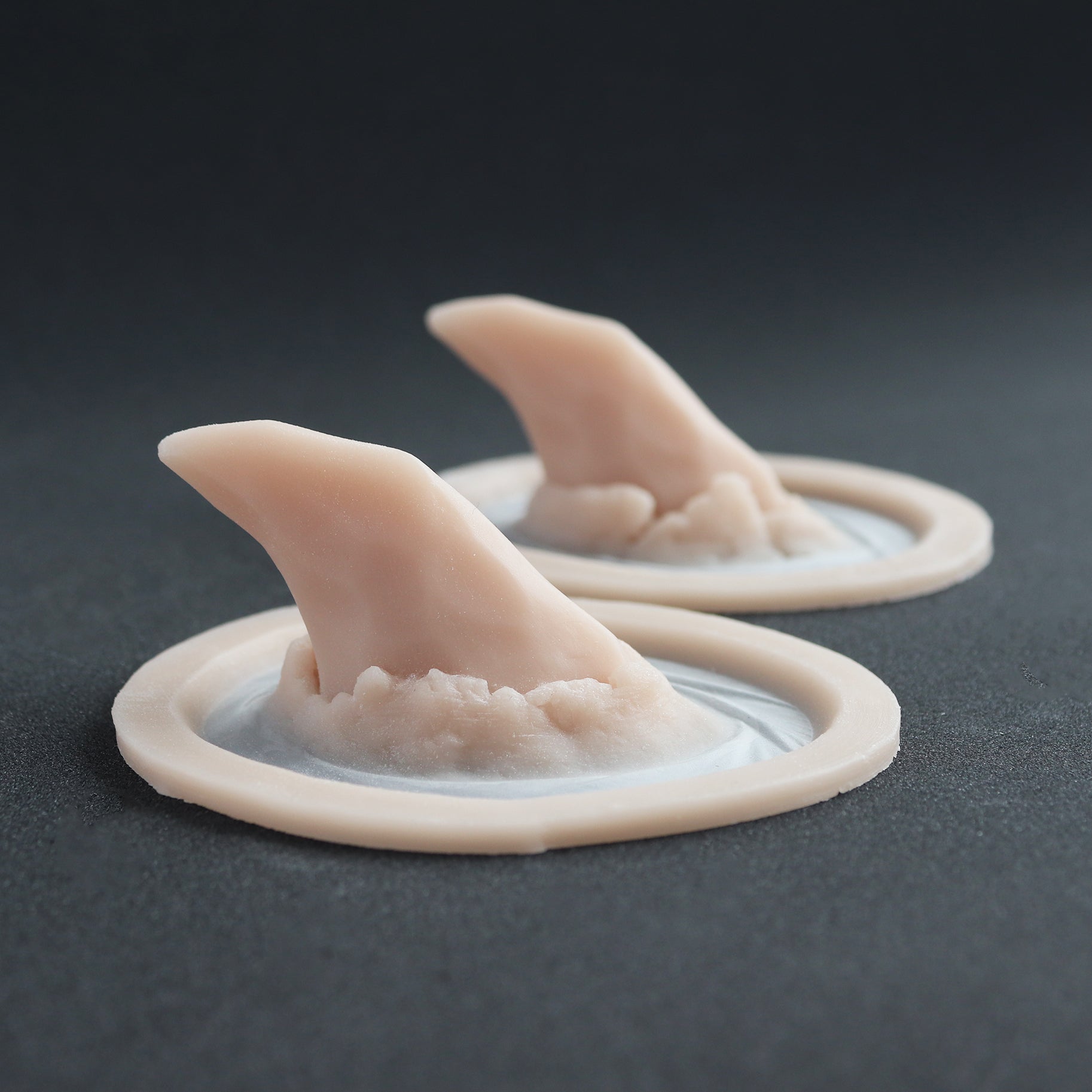 Torn Horns (Pair) - Silicone makeup prosthetic in vanilla shade on a black surface