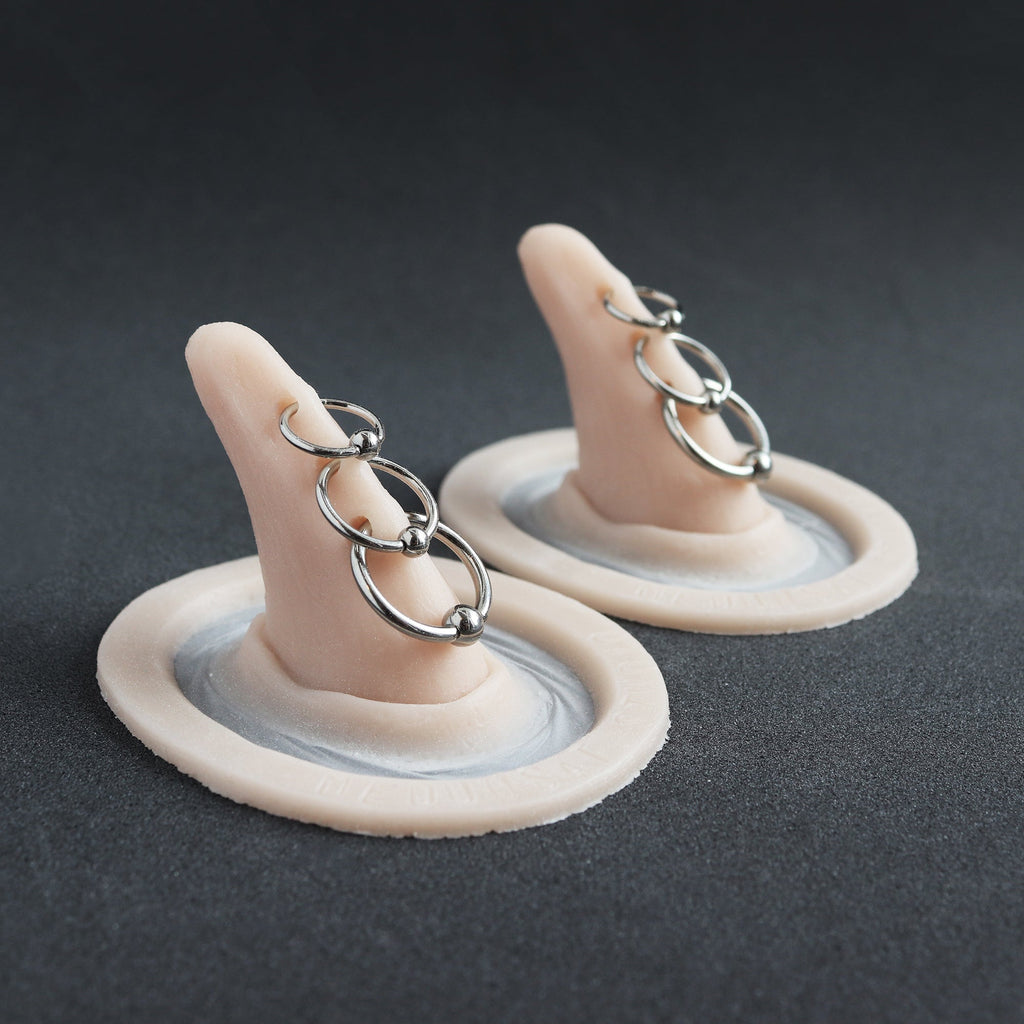 Triple Pierced Horns (Pair) - Silicone makeup prosthetic in vanilla shade on a black surface